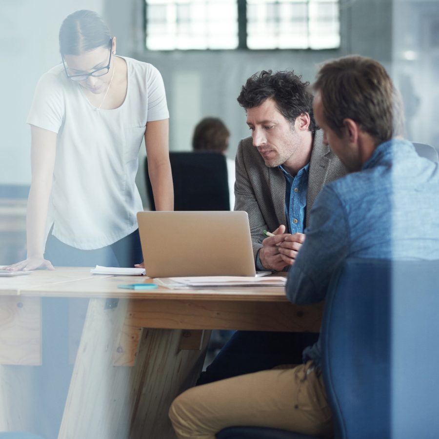 Shot of a group of colleagues talking together over a laptop in an office